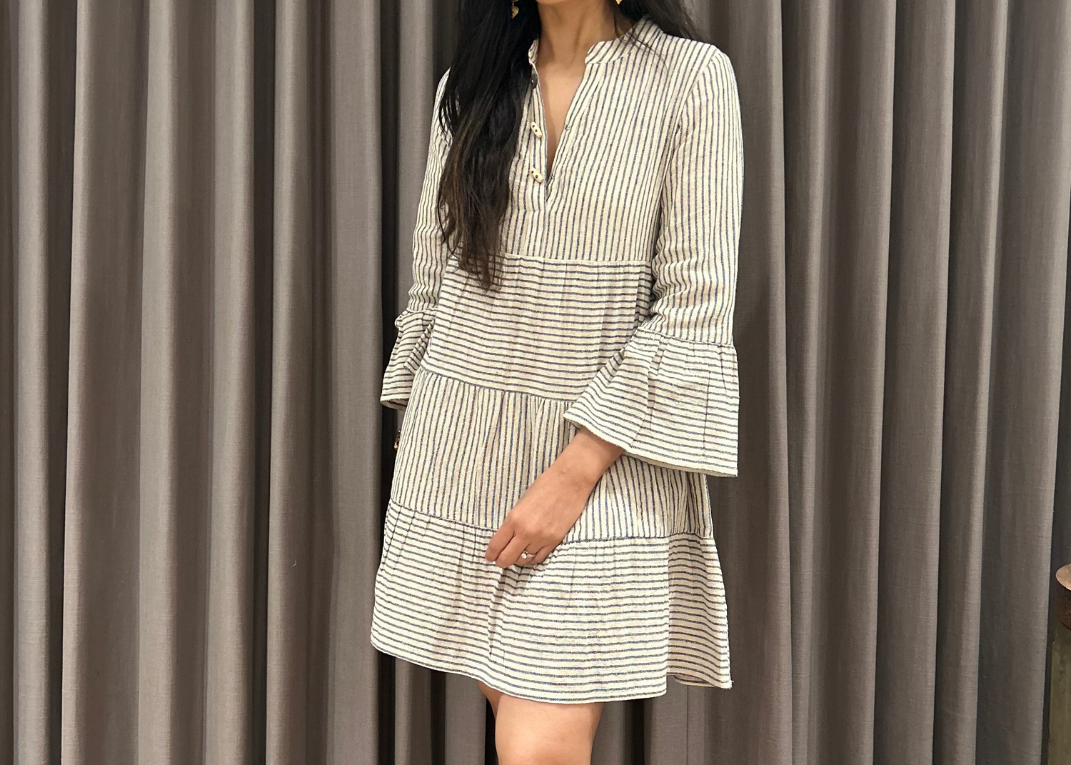 Woman in a striped dress standing in front of gray curtains